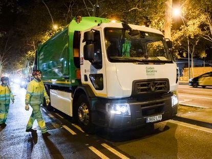 Dos trabajadores de recogida de residuos junto a uno de los nuevos camiones eléctricos adquiridos por el Ayuntamiento de Barcelona.