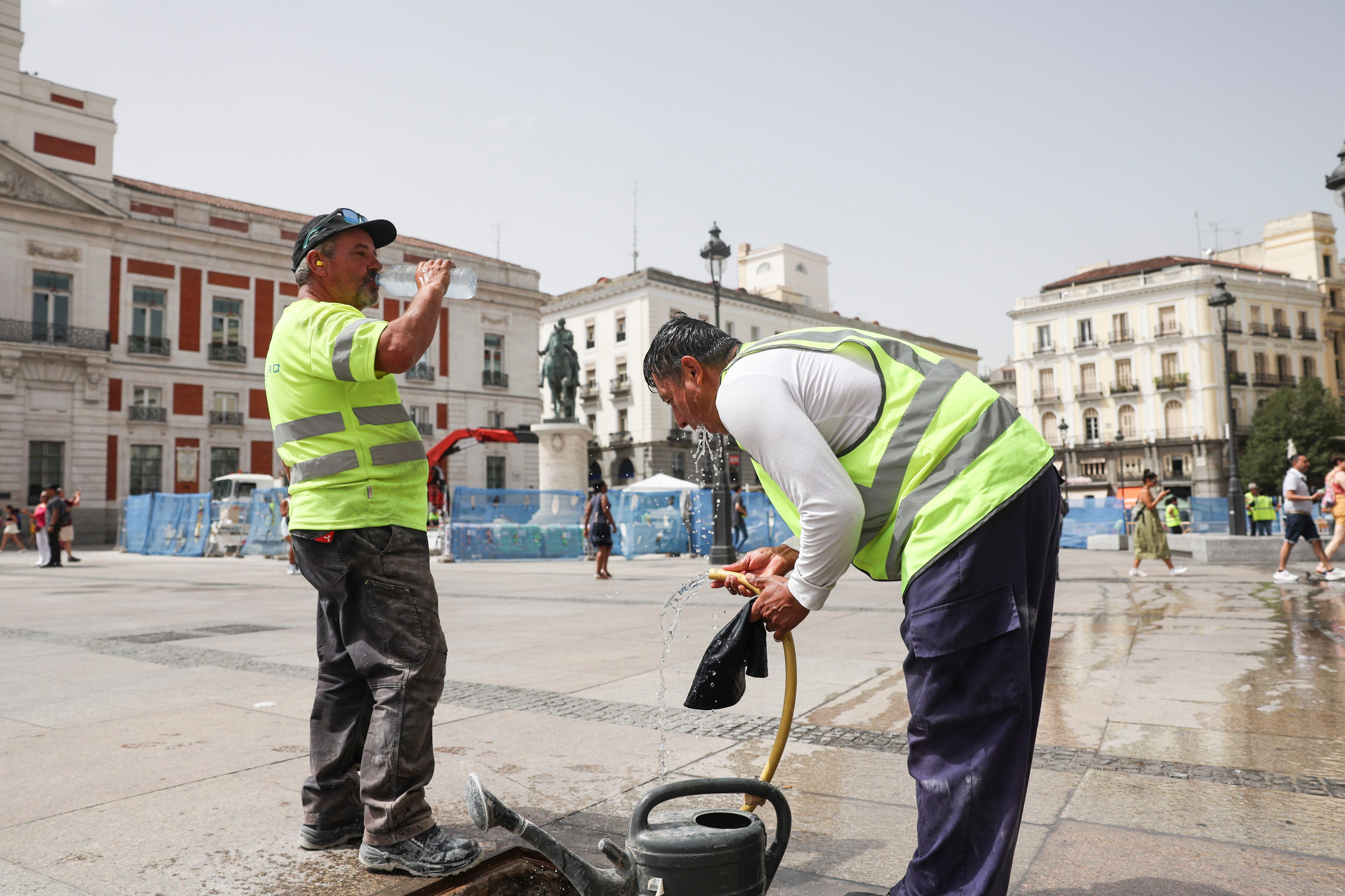 Dos trabajadores se refrescan en la  madrileña Puerta del Sol.