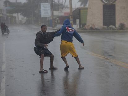 Dos jóvenes caminan con dificultad debido a los fuertes vientos durante el paso del huracán Fiona, hoy, en Nagua (República Dominicana).