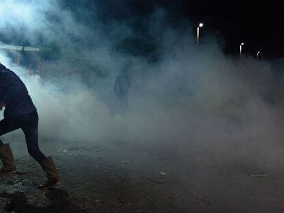 Un refugiado de Calais intenta ponerse a resguardo del gas lacrimógeno.