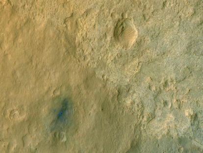 El robot 'Curiosity'. fotografiado en el suelo de Marte por la sonda orbital 'MRO', con el terreno a su alrededor (azulado) alterado por los retrocohetes de la grúa espacial que lo depositó allí.