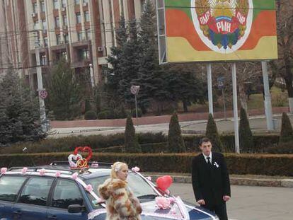 Una pareja de recién casados, en el centro de Tiráspol, frente al escudo de los independentistas.