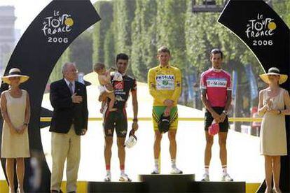 Óscar Pereiro, con su hijo Juan en brazos, Floyd Landis y Andreas Kloden, en el podio final del Tour ayer en París.