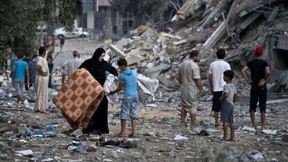 Una mujer lleva sus pertenencias con la ayuda de un niño en Gaza.