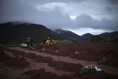 Son ya 470 muertos los que el Instituto Forense ha identificado y más de 500 víctimas que se han cobrado las lluvias en la zona montañosa del Estado de Rio en sus principales ciudades - Teresópolis, Petrópolis y Nova Friburgo. En la imagen, unos ciudadanos de la zona y miembros de los equipos de ayuda se afanan en enterrar a las victimas.