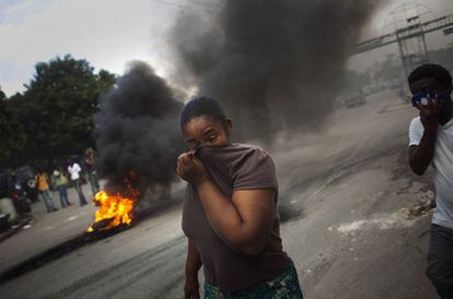 Una mujer se cubre la cara ante una barricada de neumáticos en Puerto Príncipe, adonde se extendieron las manifestaciones contra la ONU.