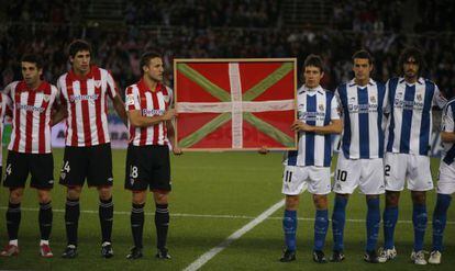 Los futbolistas del Athletic de Bilbao y de la Real Sociedad exhiben una ikurriña durante un derbi.