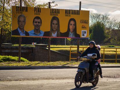 Un motociclista circula frente a propaganda electoral, en Santa Fé, Argentina.