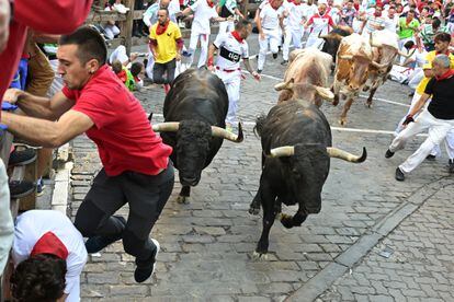 Un corredor trata de protegerse de los toros de la ganadería de Fuente Ymbro a su paso por el tramo de Telefónica.