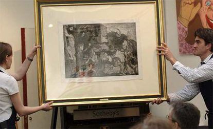 Dos trabajadores sujetan el grabado <i>La minotauromaquia</i> de Pablo Picasso, expuesto en la casa de subastas Sotheby&#39;s en Londres.