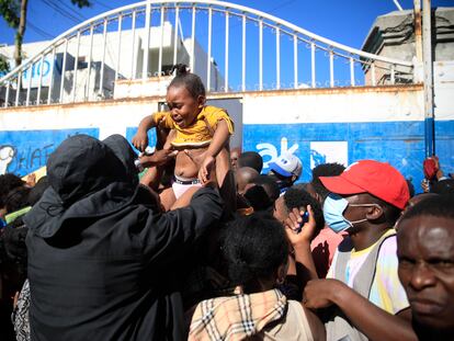 Un padre intenta pasar a su hija por la puerta de la oficina de inmigración de Haití mientras esperan su turno para solicitar un pasaporte, en Puerto Príncipe, el 9 de febrero de 2023.