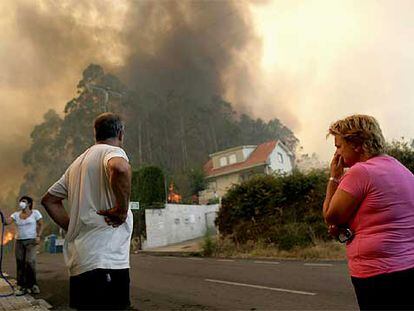 Los vecinos observan un incendio en la urbanización Aldea Nova, en el concello de Ames, A Coruña.