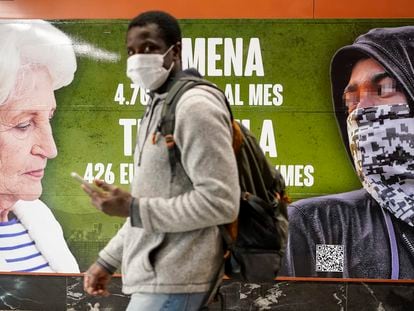 Un hombre pasa ante el cartel contra los menores extranjeros colocado por Vox en una estación de tren de Madrid.