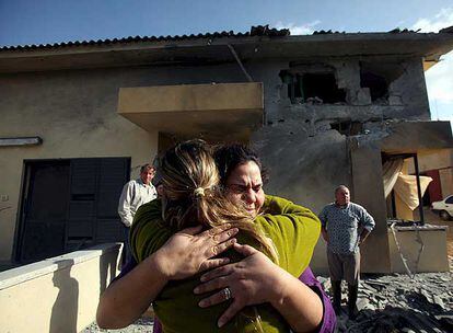 Dos mujeres se abrazan delante de una casa dañada el 24 de diciembre por un cohete palestino en Tequma, en el sur de Israel.