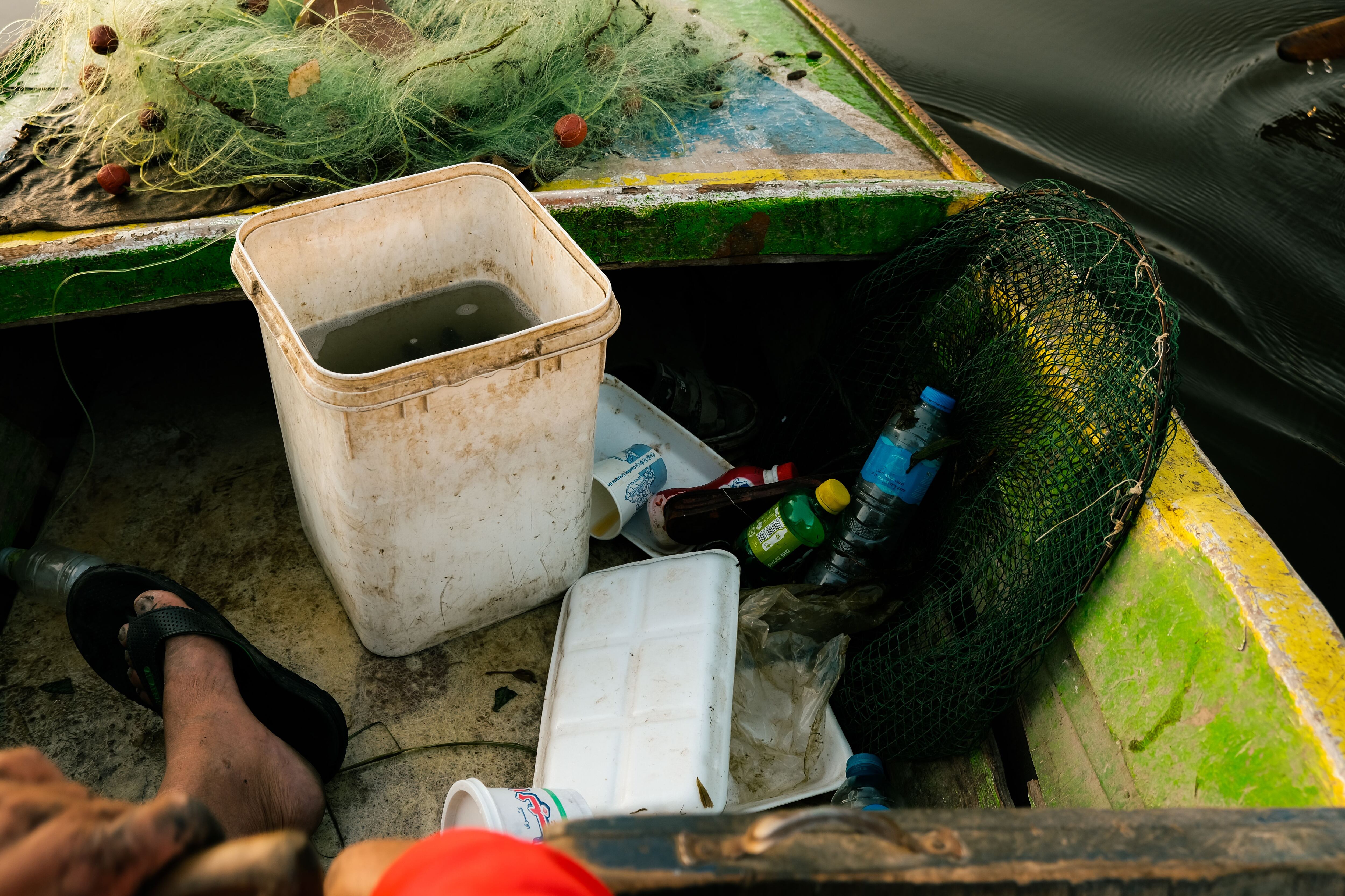 Restos de basura que Arafa Saber ha rescatado de El Nilo junto al cubo donde almacena su pesca. 