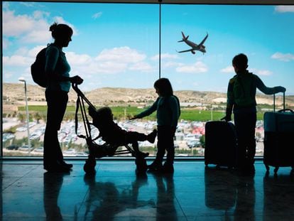 Una madre espera con sus hijos a embarcar en una terminal de un aeropuerto.