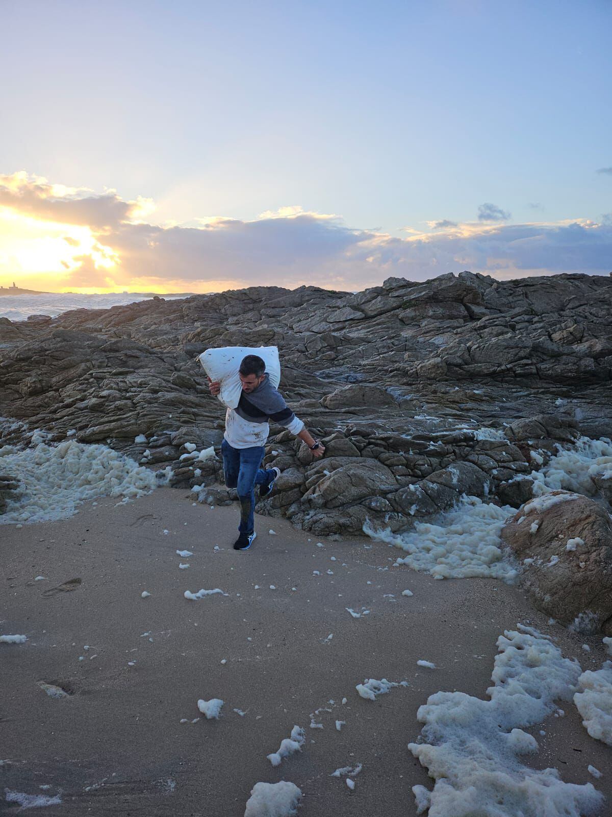 Rodrigo Fresco retira de la zona de afectada por las mareas un saco de 'pellets' en Corrubedo, el pasado 13 de diciembre, en una foto tomada por su pareja.