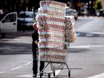 Un reponedor lleva un carro con papel higiénico a un comercio en Málaga.