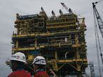 Employee pass in front of the finished Abkatun-A2 oil platform at the Mcdermott International Inc. fabrication facility in Altamira, Tamaulipas state, Mexico, on Friday, Nov. 2, 2018. Mcdermott International was awarded the $454 million contract for engineering, procurement, construction and installation for Abkatun-A2 from Petroleos Mexicanos (Pemex) in 2016. Pemex is expected to start operating the oil platform in April 2019. Photographer: Luis Antonio Rojas/Bloomberg