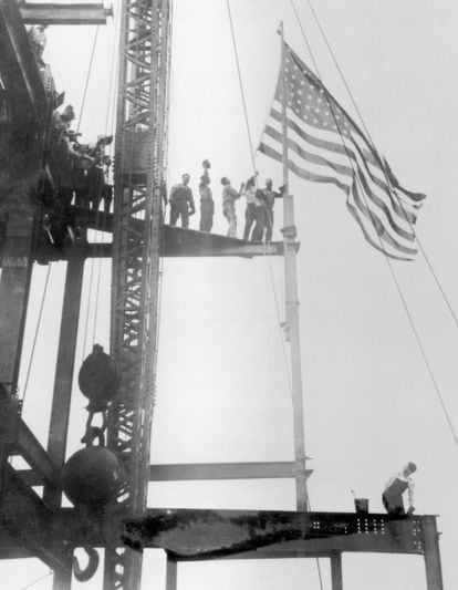 Obreros izan la bandera de Estados Unidos sobre la estructura del Empire State Builging. El coloso se construyó entre 1930 y 1931, en plena Gran Depresión y lucha de los constructores por ostentar el edificio más alto.