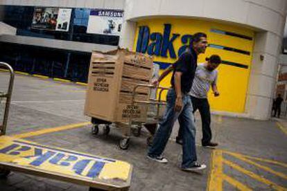 Varias personas salen tras comprar electrodomésticos el 9 de noviembre de 2013, en una de las sedes de la cadena de tiendas Daka, en Caracas (Venezuela).