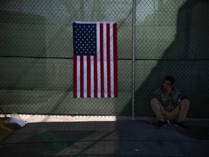 Un migrante reposa junto a una bandera de Estados Unidos, en una calle de El Paso, el pasado 21 de diciembre.