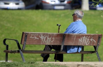 Un hombre sentado en el banco de un parque.