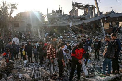 Varios palestinos examinan una zona que fue bombardeada antes del alto al fuego que se ha iniciado hoy, este viernes en Rafah. 