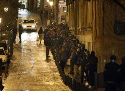 Decenas de personas esperan para cenar en la Real Hermandad del Refugio y Piedad de Madrid, en la calle de la Corredera Baja de San Pablo (Centro).