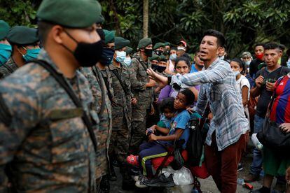 Un migrante hondureño con sus hijos frente a las fuerzas de seguridad de Guatemala.