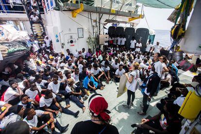 Miembros de las ONG informan al grupo de migrantes rescatados, en la cubierta del barco.