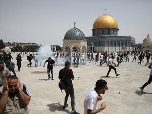 Decenas de palestinos corren tras el lanzamiento de granadas aturdidoras por agentes israelíes, este viernes en la Explanada de las Mezquitas de Jerusalén.