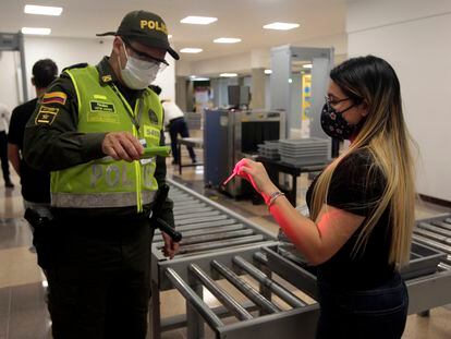 Un oficial de policía verifica la identificación de un pasajero en el aeropuerto Olaya Herrera en 2020 en Medellín, Colombia.