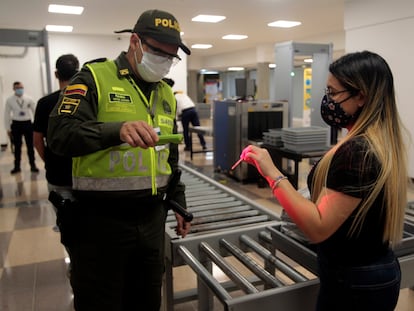 Un oficial de policía verifica la identificación de un pasajero en el aeropuerto Olaya Herrera en 2020 en Medellín, Colombia.