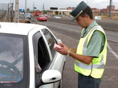 Un agente de la Guardia Civil mira la documentaci&oacute;n de un conductor.