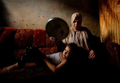 Una mujer palestina abanica a su hija en medio de una ola de calor e importantes cortes de energía en la ciudad de Gaza, el lunes.