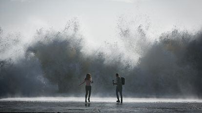 Una pareja corría tras hacerse un selfi en el espigón de la playa de Bogatell, en Barcelona, durante la borrasca 'Gloria', en enero de 2020.