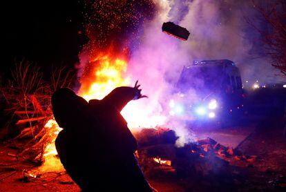 Un manifestante tira una piedra a un furgón policial, durante los disturbios en Ucrania por la llegada de 72 evacuados de la ciudad china de Wuhan.