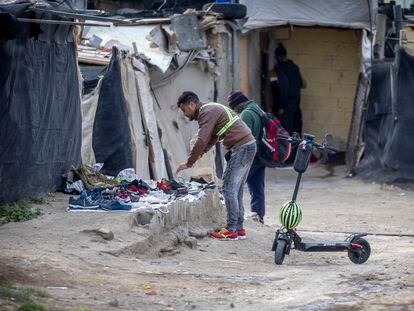 Dos migrantes buscan calzado en el asentamiento de Atochares, en la localidad de San Isidro, dentro del municipio de Níjar, Almería.