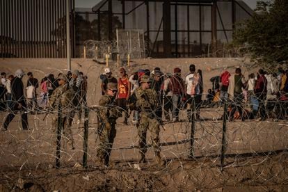 Soldados del ejército estadounidense y migrantes en el paso fronterizo entre Ciudad Juárez y El Paso.