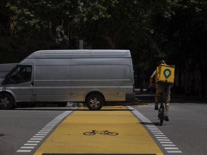 Un repartidor de Glovo i una furgoneta al nou carril bici de Pau Claris. 