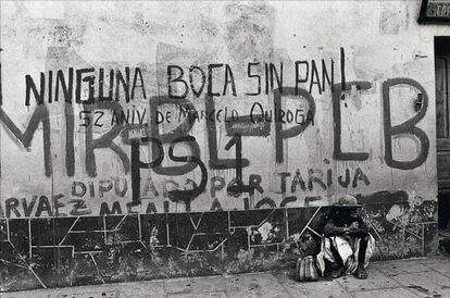 Raúl Ávila recurre a un antiguo aforismo: "Todo lo que no es universal es folclórico". En la foto, una mujer sentada delante de una pared con pintadas, en una calle de Tarija, Bolivia.