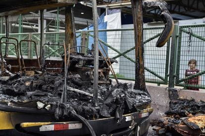 Un niño observa los restos de un autobús quemado en Guayaquil. 