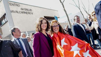 La presidenta madrileña, Isabel Díaz Ayuso, junto a una mujer envuelta en la bandera de la Comunidad de Madrid, el 23 de marzo, en la presentación del centro de salud Navalcarnero II.
