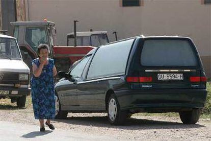 Una vecina de Riba de Saelices pasa junto a uno de los coches fúnebres que iban a recoger los cadáveres de las víctimas.