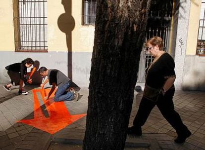 Unos artistas colocan flechas para señalar lugares del distrito de Arganzuela.