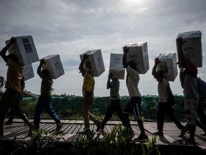 Unos voluntarios llevan urnas de cartón a los colegios electorales en Asmat, al sur de la provincia indonesia de Papúa, el 13 de febrero.
