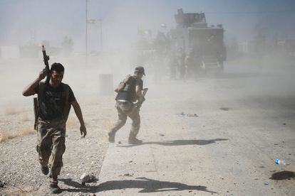 Dos soldados iraquíes corren a esconderse durante los enfrentamientos con los combatientes del Estado Islámico en Bartella, al este de Mosul (Irak), el 20 de octubre.