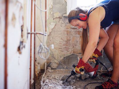Una mujer utiliza un martillo neumático para levantar el suelo de su casa.