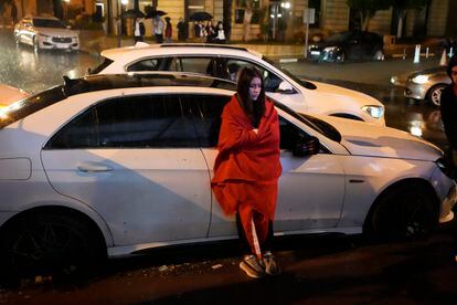 Final de fiesta: una joven, arropada con la bandera de Marruecos, se apoya en un coche aparcado en una calle de Rabat.  